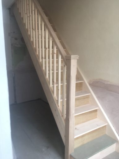 Wooden staircase with a simple balustrade leading to an upper floor.